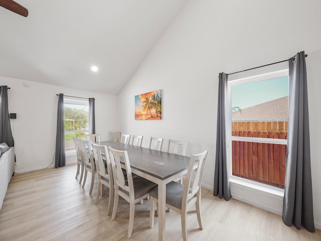 dining area with high vaulted ceiling and light hardwood / wood-style flooring