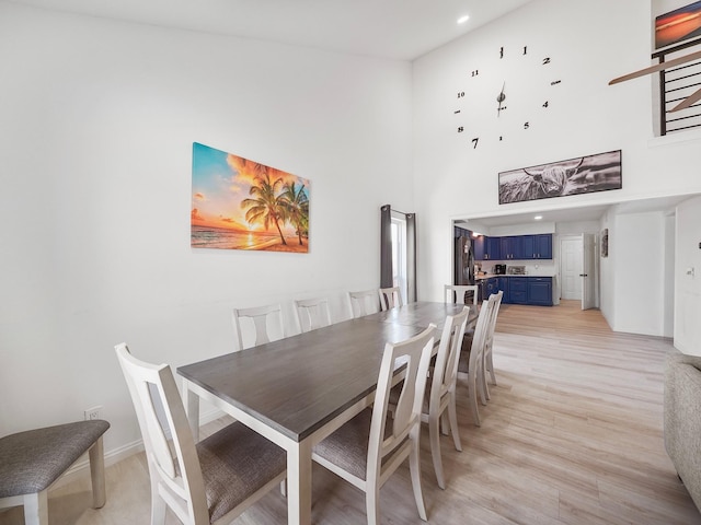 dining room featuring a towering ceiling and light wood-type flooring