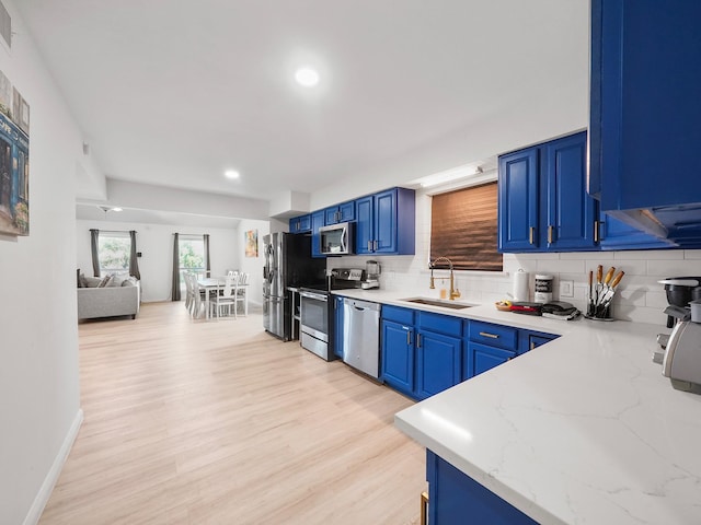 kitchen featuring blue cabinetry, sink, stainless steel appliances, and tasteful backsplash