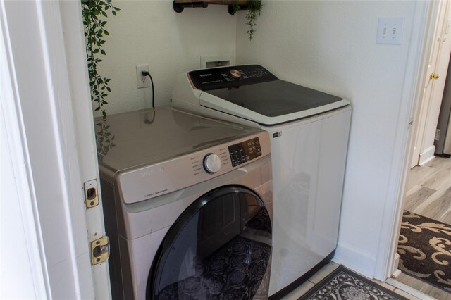 clothes washing area featuring washer and clothes dryer and light hardwood / wood-style flooring