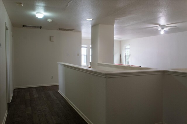 hallway with a textured ceiling and dark hardwood / wood-style floors