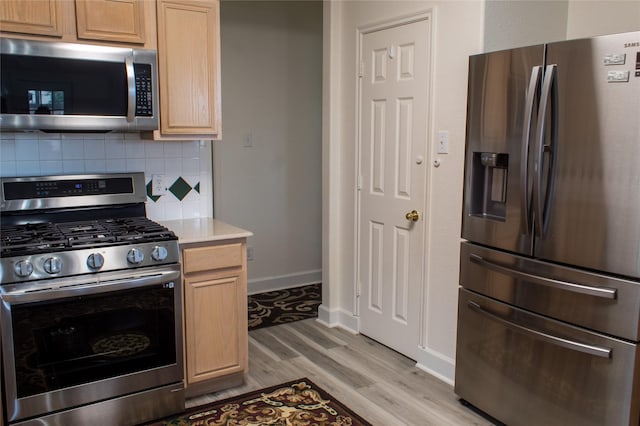 kitchen with light hardwood / wood-style floors, light brown cabinetry, appliances with stainless steel finishes, and tasteful backsplash