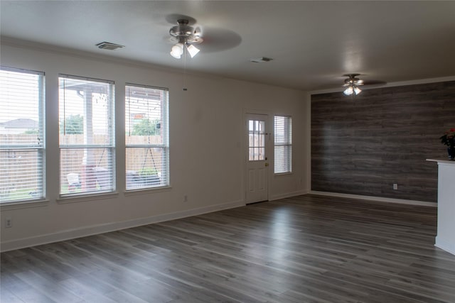 empty room featuring ceiling fan, dark hardwood / wood-style flooring, wooden walls, and ornamental molding