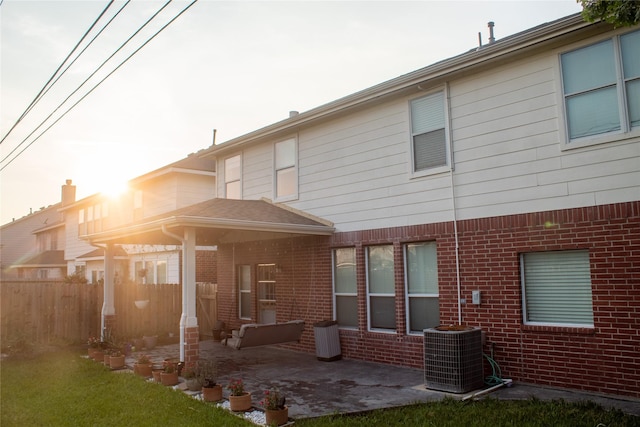 rear view of house with central air condition unit and a patio