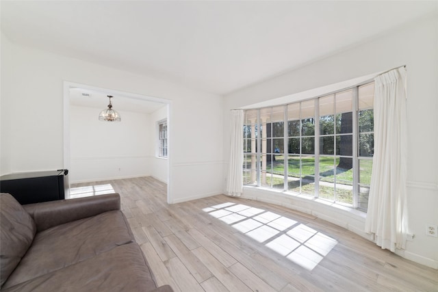 unfurnished living room with a chandelier and light wood-type flooring