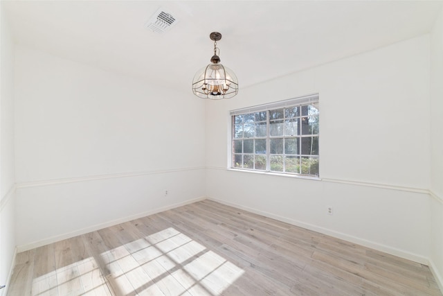 empty room with a chandelier and light wood-type flooring