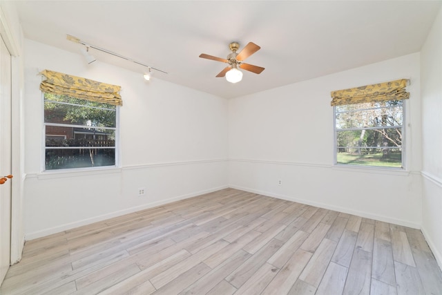 unfurnished room featuring rail lighting, light hardwood / wood-style floors, ceiling fan, and a healthy amount of sunlight