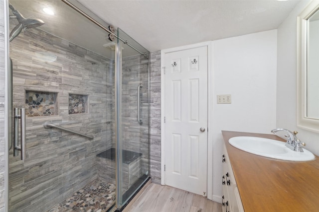 bathroom featuring hardwood / wood-style floors, vanity, a textured ceiling, and a shower with door