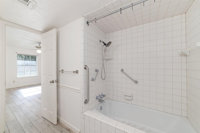 bathroom with wood-type flooring, tiled shower / bath, and ceiling fan