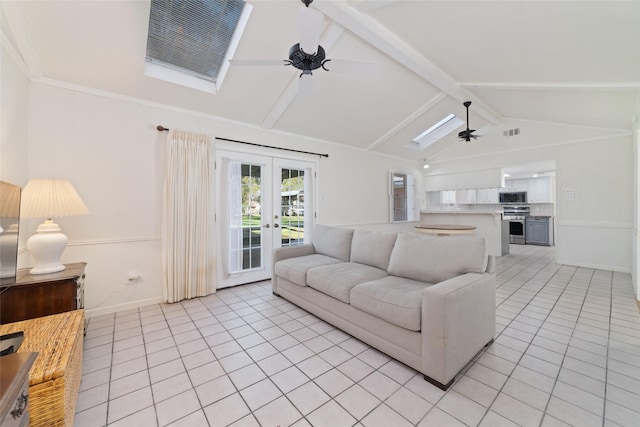 tiled living room with french doors, lofted ceiling with skylight, and ceiling fan