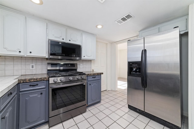 kitchen with backsplash, white cabinets, stainless steel appliances, and light tile patterned floors