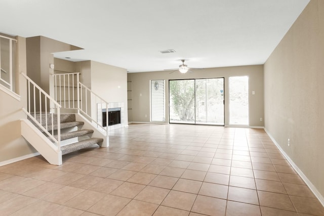 unfurnished living room featuring ceiling fan, light tile patterned floors, and a fireplace