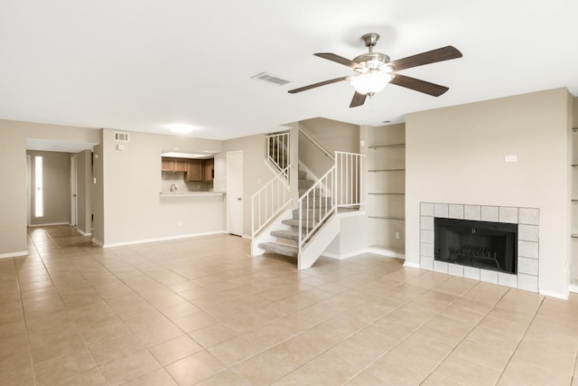 unfurnished living room featuring light tile patterned flooring, built in features, and a tiled fireplace