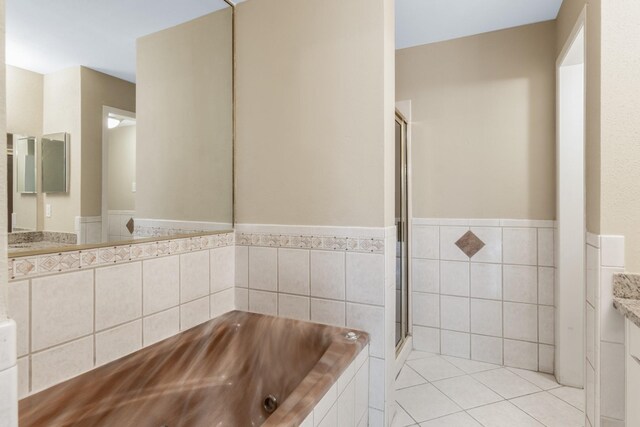 bathroom with vanity, tile patterned floors, tile walls, and tiled tub