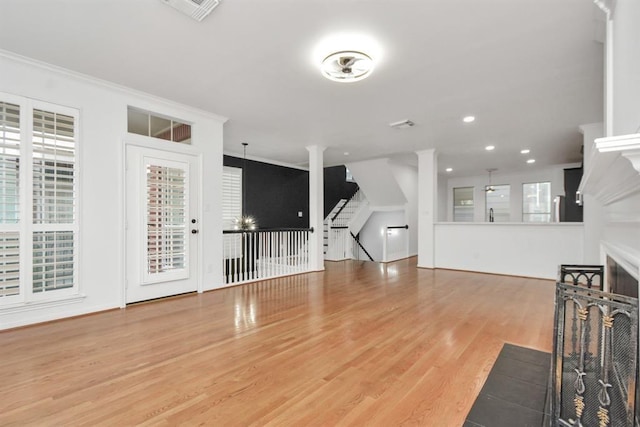 unfurnished living room featuring recessed lighting, wood finished floors, visible vents, ornamental molding, and stairs