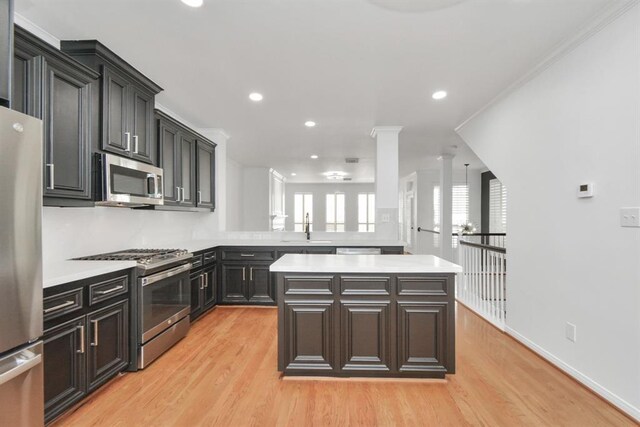 kitchen with light wood-type flooring, stainless steel appliances, a kitchen island, and sink