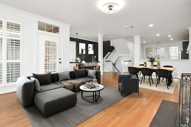 living room with crown molding, stairs, wood finished floors, ornate columns, and recessed lighting