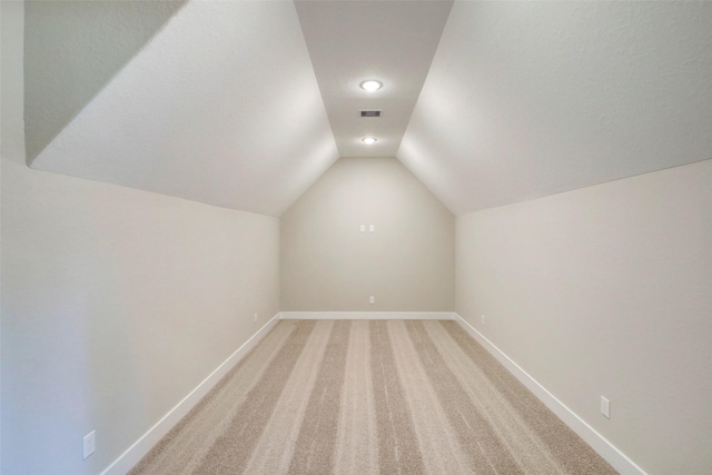 bonus room with light colored carpet and lofted ceiling