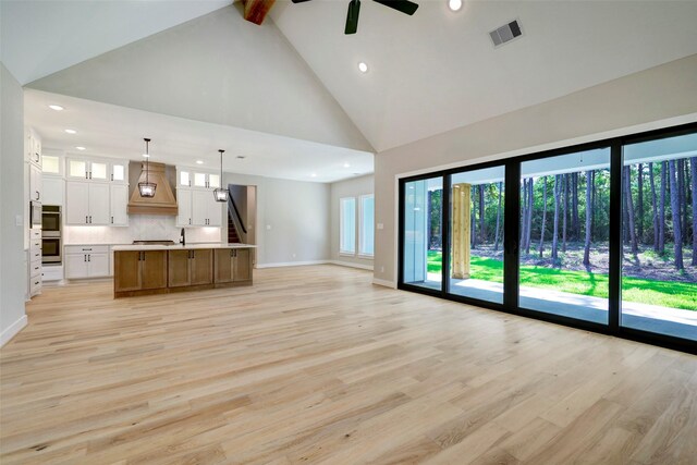 unfurnished living room featuring beam ceiling, ceiling fan, and light hardwood / wood-style flooring