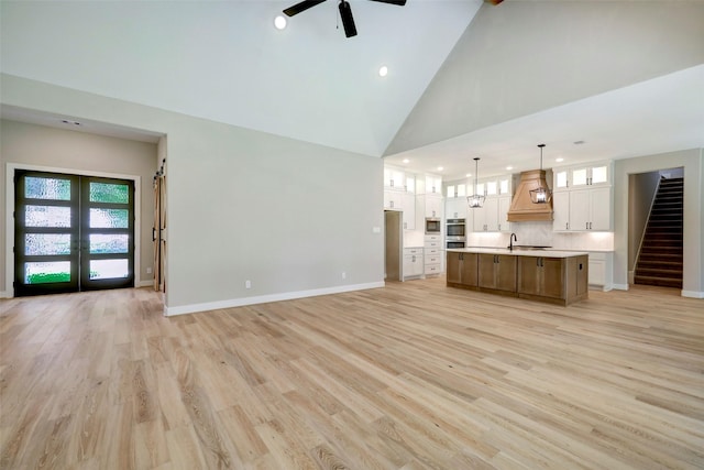 unfurnished living room featuring french doors, high vaulted ceiling, light wood-type flooring, ceiling fan, and sink