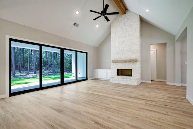 unfurnished living room with light hardwood / wood-style flooring, high vaulted ceiling, beam ceiling, ceiling fan, and a stone fireplace