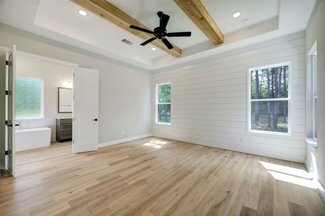 unfurnished bedroom featuring ceiling fan, a tray ceiling, light hardwood / wood-style floors, and beam ceiling