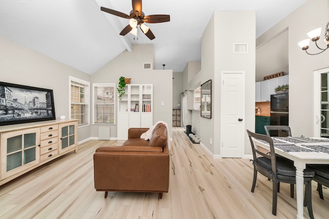 living room featuring high vaulted ceiling, beam ceiling, ceiling fan with notable chandelier, and light hardwood / wood-style flooring