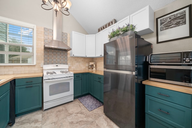 kitchen featuring wall chimney exhaust hood, lofted ceiling, stainless steel appliances, decorative backsplash, and white cabinets