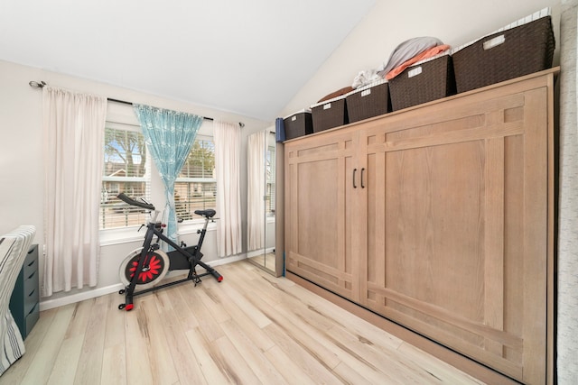 workout room with lofted ceiling and light hardwood / wood-style flooring