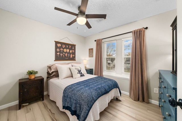 bedroom featuring ceiling fan, light hardwood / wood-style floors, and a textured ceiling