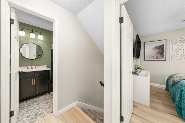 bathroom featuring wood-type flooring, vanity, and a textured ceiling