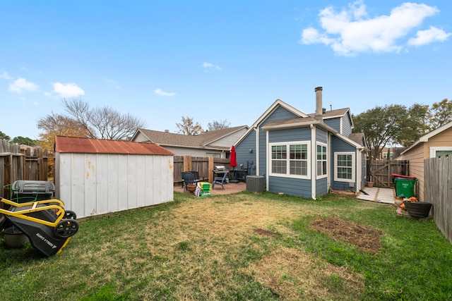 back of house featuring central AC, a yard, and a shed