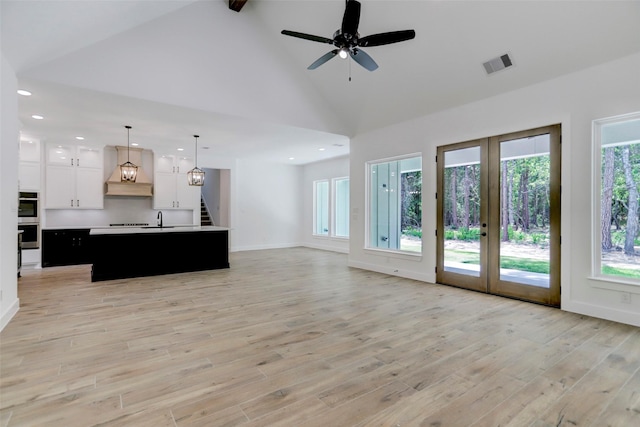 unfurnished living room with ceiling fan, light wood-type flooring, sink, and french doors