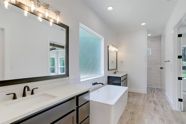 bathroom with ceiling fan, hardwood / wood-style floors, vanity, and shower with separate bathtub