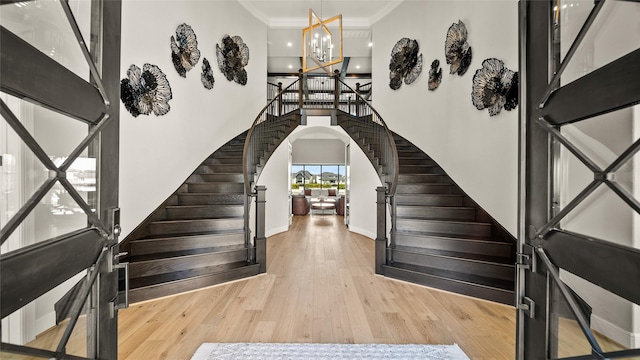 foyer with crown molding, light hardwood / wood-style floors, and an inviting chandelier