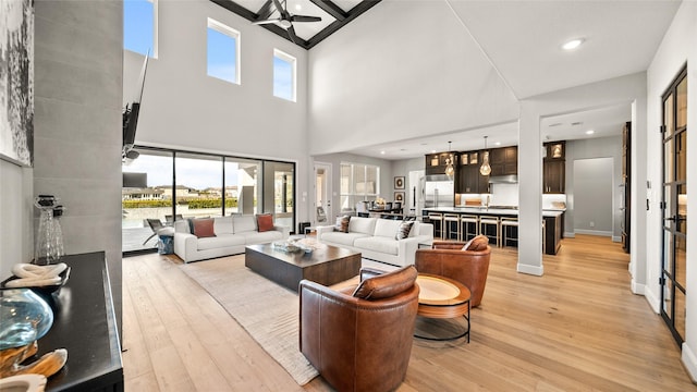 living room with a high ceiling, light hardwood / wood-style floors, and ceiling fan