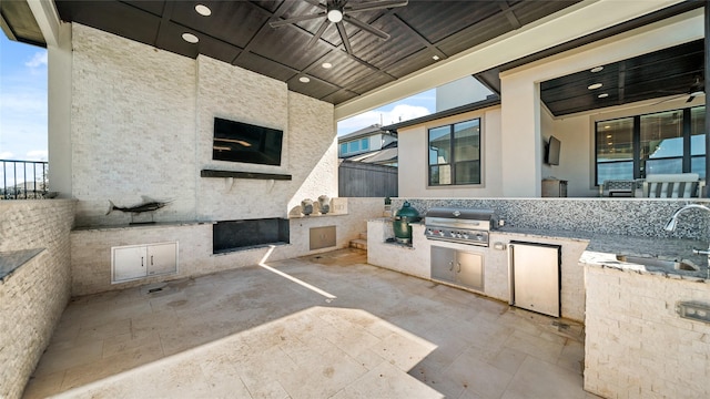 view of patio featuring a grill, ceiling fan, sink, and exterior kitchen