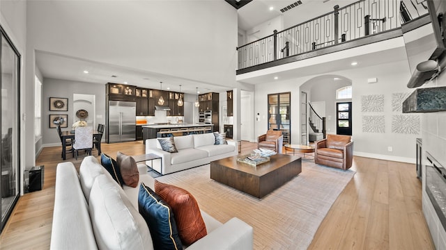 living room featuring a towering ceiling and light wood-type flooring