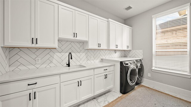 laundry room with washer and dryer, cabinets, and sink