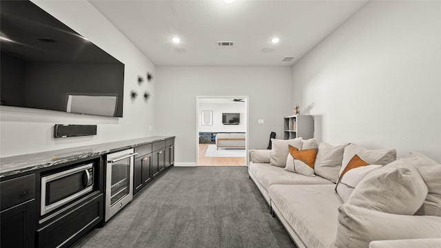 living room featuring ceiling fan, beverage cooler, and dark carpet