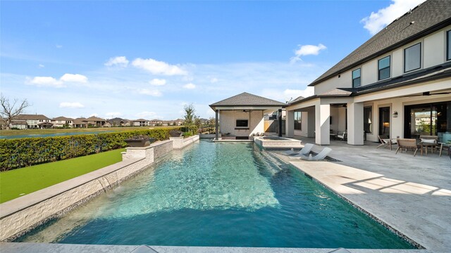 view of pool featuring a patio area, an in ground hot tub, and exterior fireplace