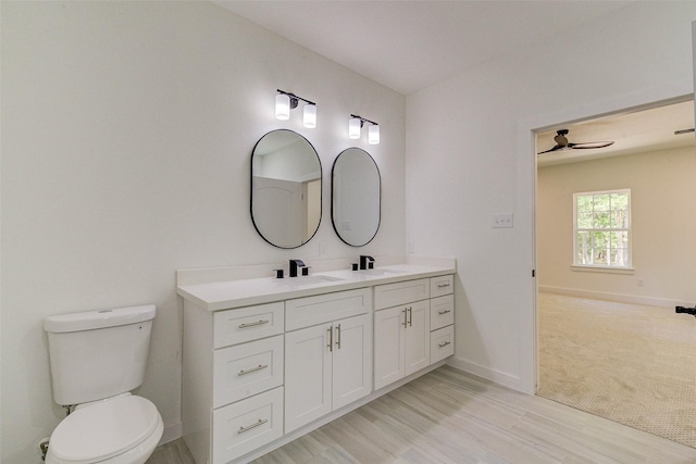 full bath with double vanity, a sink, toilet, and baseboards