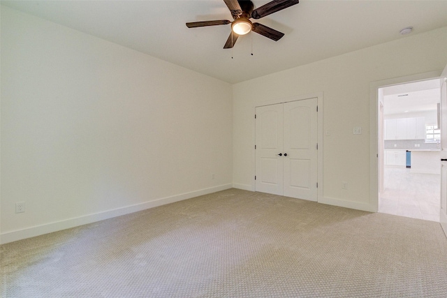 unfurnished bedroom featuring baseboards, ceiling fan, a closet, and light colored carpet