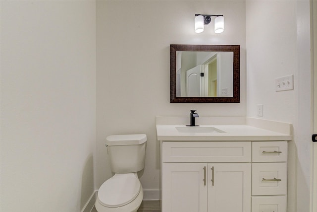 bathroom featuring toilet, baseboards, and vanity