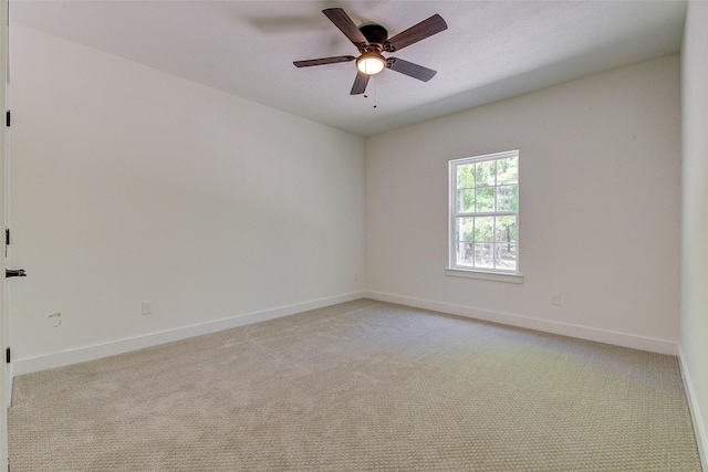 spare room with baseboards, a ceiling fan, and light colored carpet