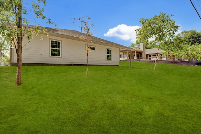 back of house featuring a lawn and fence