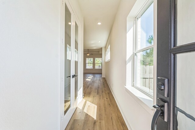 hallway featuring recessed lighting, light wood finished floors, baseboards, and french doors