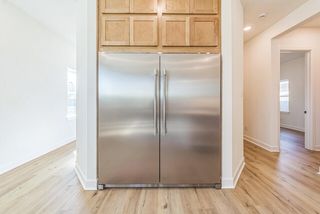 kitchen with light wood-type flooring, stainless steel built in refrigerator, and light brown cabinetry