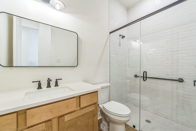 bathroom featuring toilet, a shower with shower door, and vanity