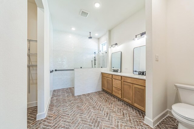 bathroom with a tile shower, vanity, and toilet